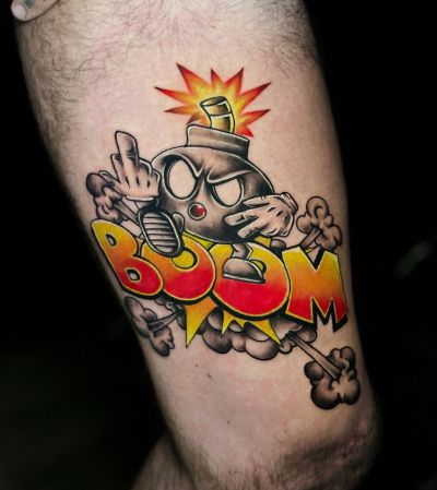 Colorful cartoon bomb tattoo with red and yellow BOOM lettering on a leg